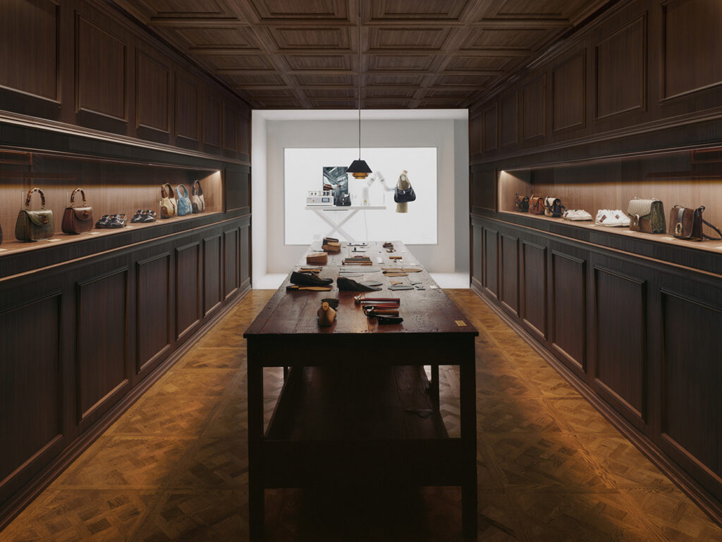 《Gucci Storia》展览匠艺回廊内景，两侧壁龛陈列Bamboo 1947、Jackie 1961等经典手袋，中央工作台重现佛罗伦萨工匠场景